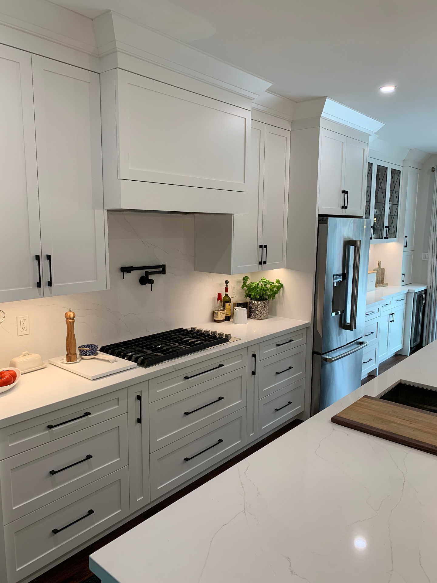 White shaker kitchen with black hardware and integrated hood